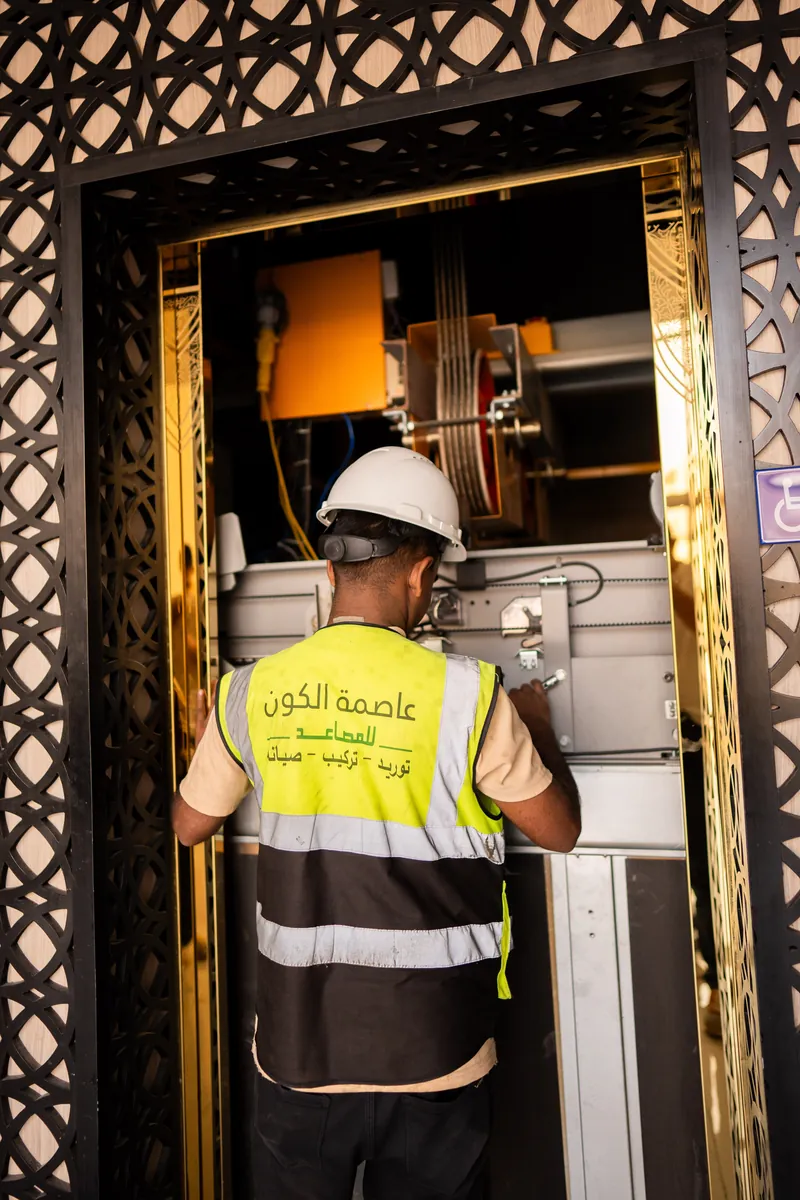 فني يعمل على أعلى الكابينة — عاصمة الكون للمصاعد